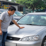 Người mua đang kiểm tra một chiếc ô tô cũ tại bãi xe trước khi mua