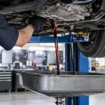 Kỹ thuật viên xả dầu hộp số tự động dưới gầm xe sedan